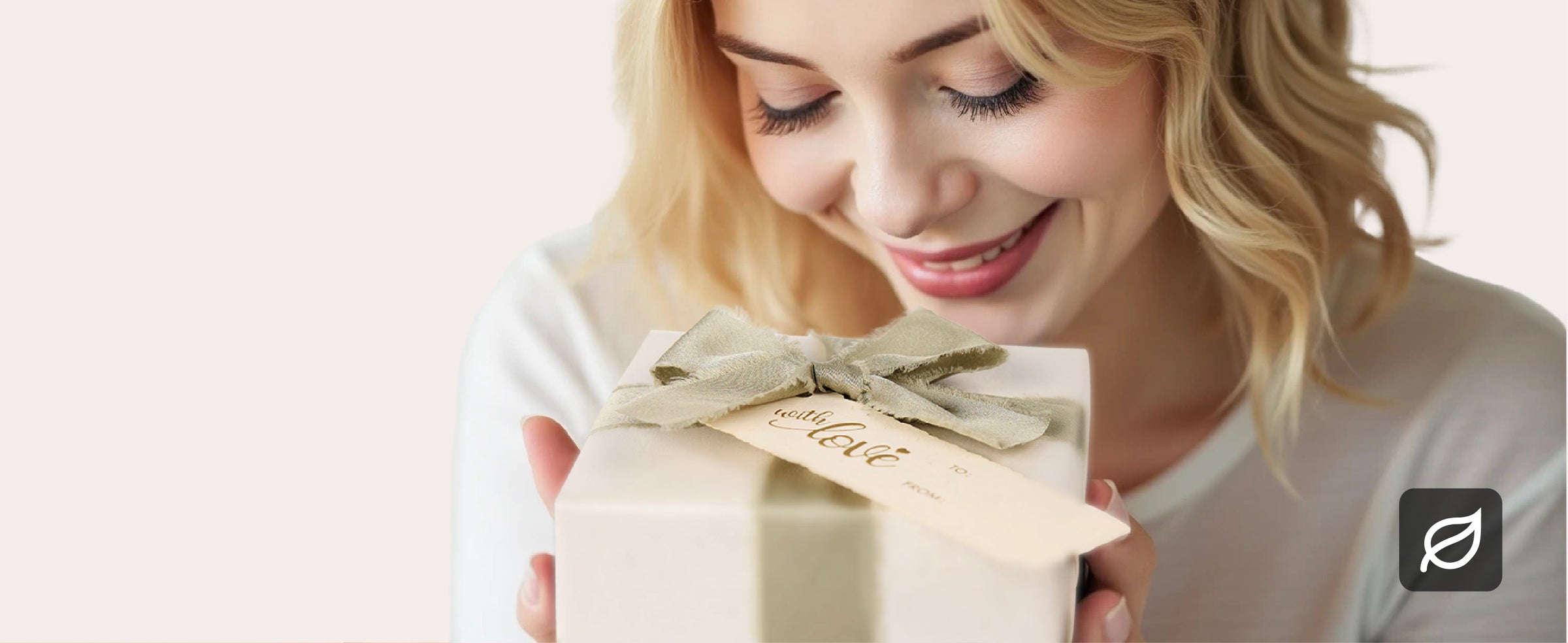 Woman holding a pearly white gift wrapped with a sage fabric bow and cream gift tag