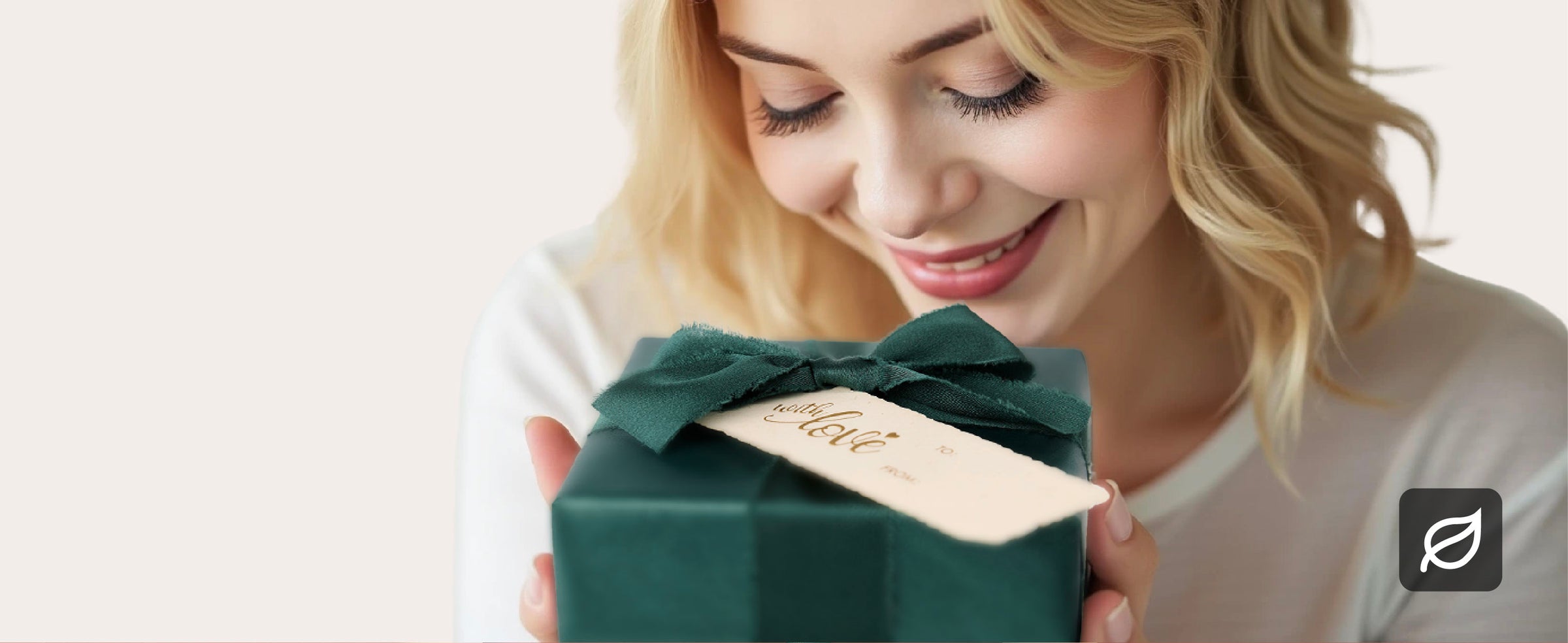 Woman holding a gift wrapped in lustrous green paper with a matching fabric bow and cream tag