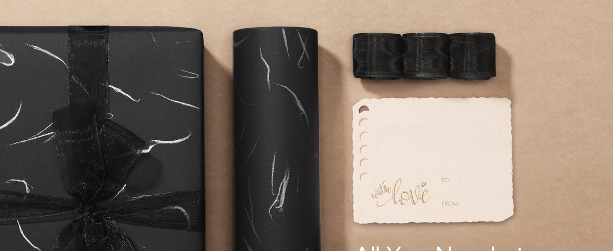 Black silver-accented wrapping paper set with sheer ribbon, scalloped tags, and a wrapped gift.