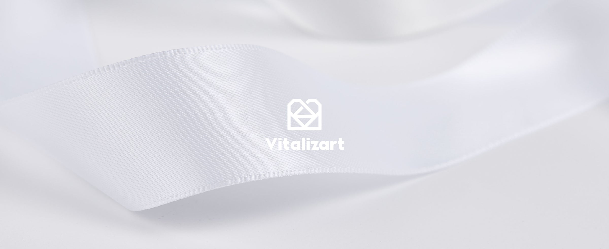 Off-white satin ribbon shown on a cardboard spool and feeding through a brown dispenser box.