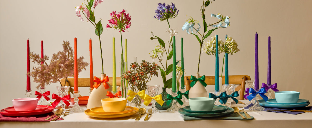 Rainbow satin ribbon bows decorate glassware and vases on a colorful floral dining table