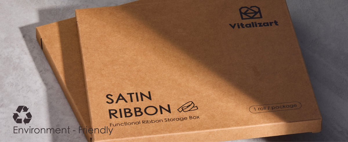 Blue satin ribbon dispenses from a kraft storage box as a hand cuts it with scissors.