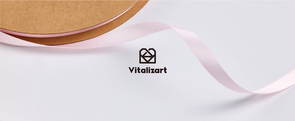 Light pink satin ribbon unrolling from a kraft reel above the Vitalizart logo