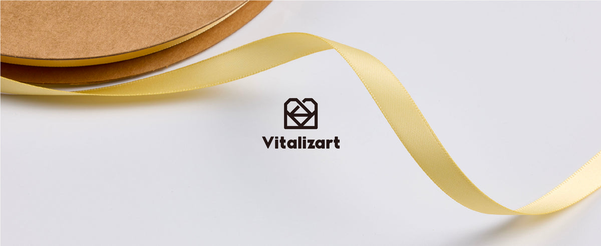 Champagne satin ribbon unfurling from a brown cardboard spool with Vitalizart branding