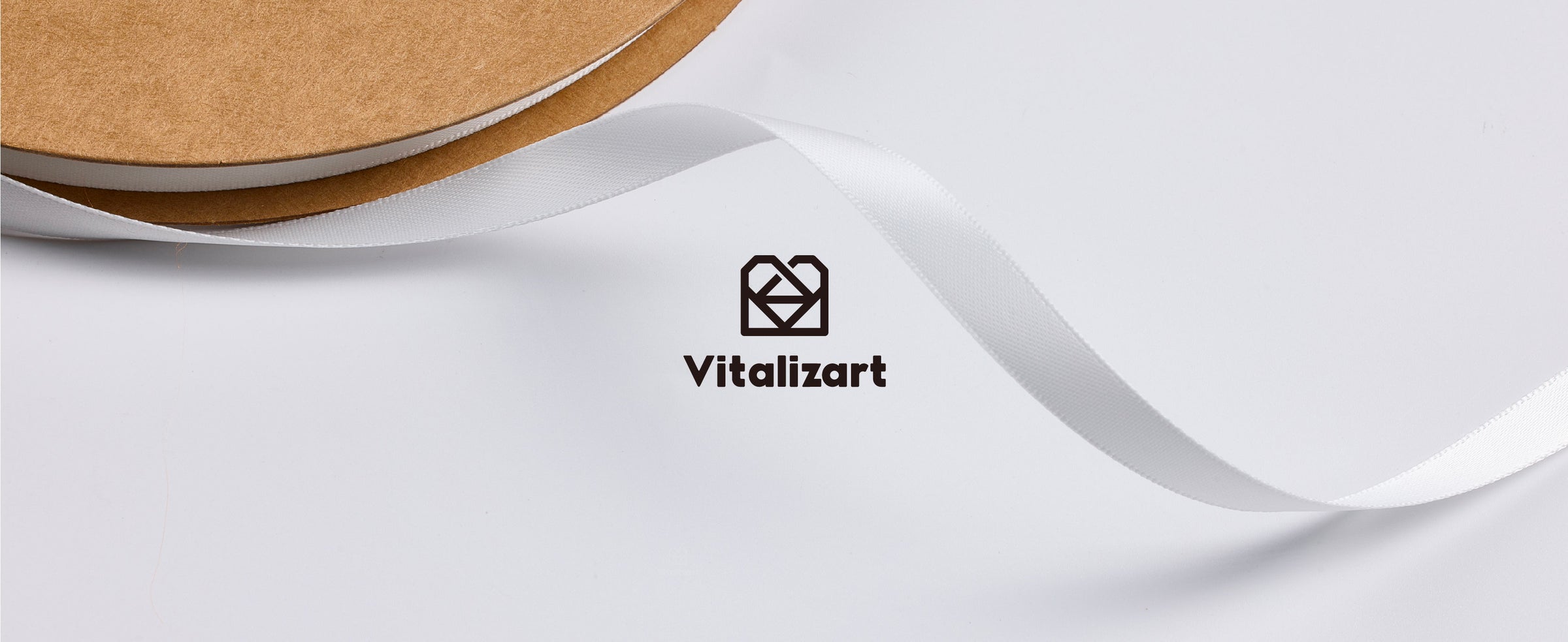 Close view of off-white satin ribbon unwinding from a kraft cardboard spool