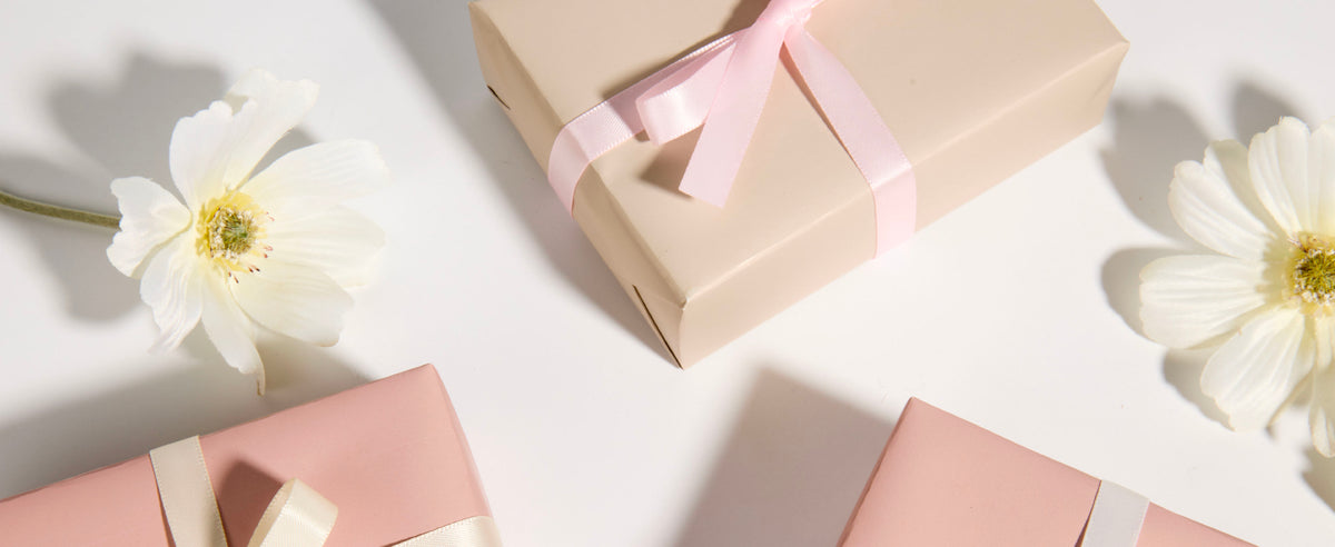 Wrapped gifts finished with layered bows made from the pink and white double-faced satin ribbon set