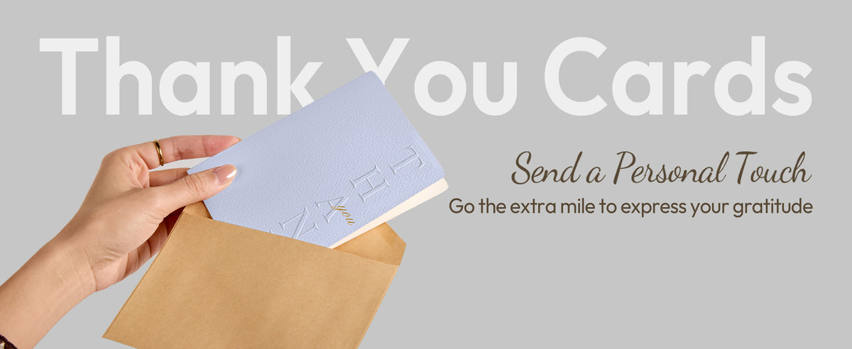 Hand placing a textured pale blue-gray embossed thank-you card into an open kraft envelope