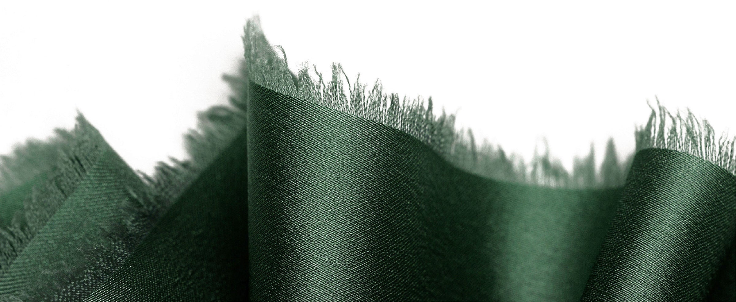 Dark green satin ribbon close-up highlighting its fine weave and irregular frayed edge