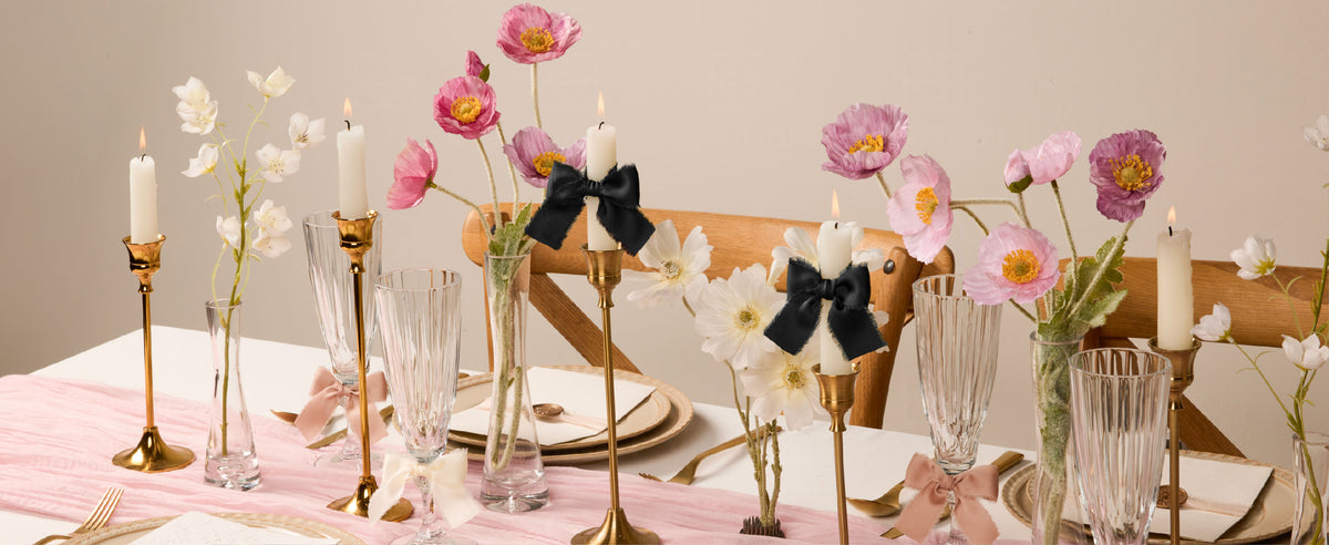 Black frayed satin ribbon bows accent candles in a floral table setting with blush and ivory bows.