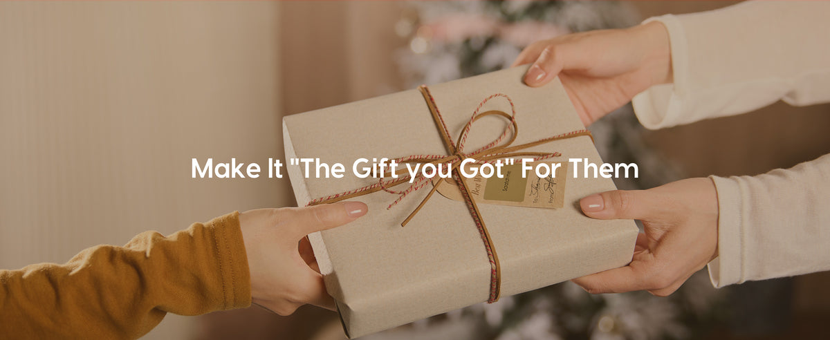 Hands exchange a beige textured-paper gift tied with brown ribbon, red twine, and a kraft tag.