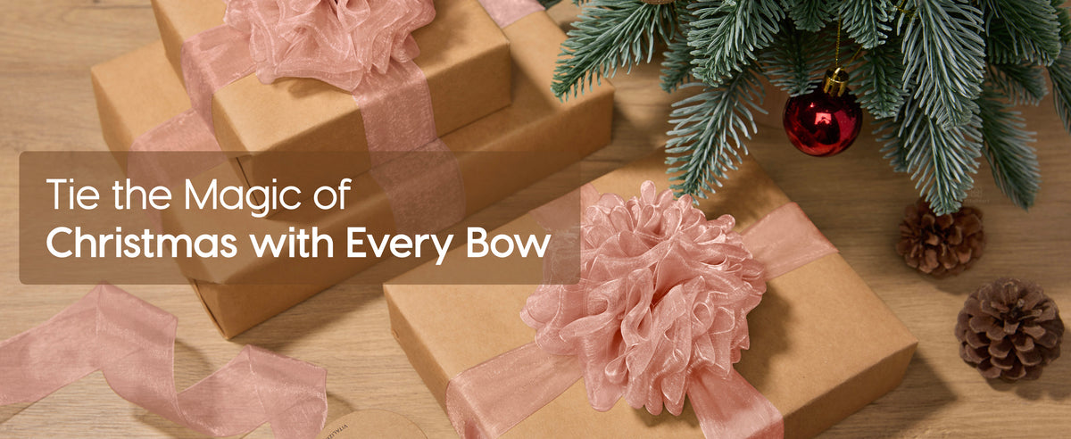Christmas gifts in kraft paper tied with dusty rose organza ribbon and a large bow under evergreen branches
