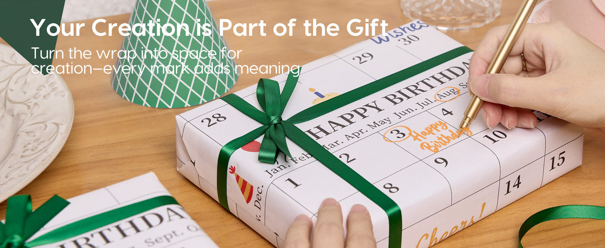 Hands write on calendar-print birthday wrapping paper tied around a gift with a green satin ribbon.