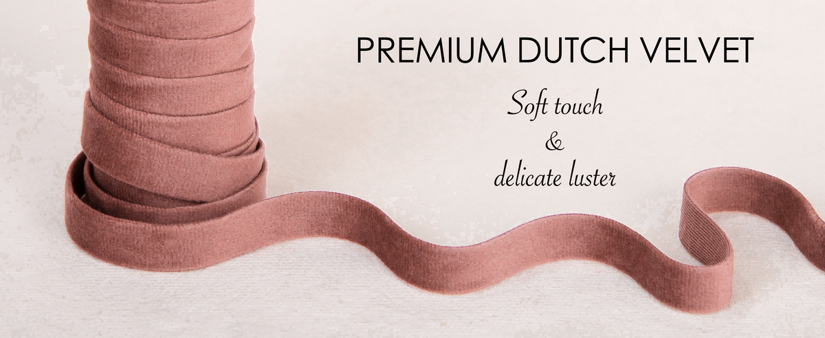 Close-up of dusty rose velvet ribbon with a soft sheen and pinked edge on white fabric