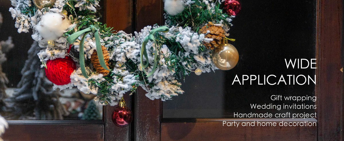 Green velvet ribbon bows decorate a snowy evergreen wreath with pinecones, lights, and ornaments.