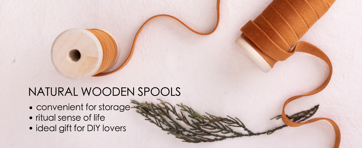 Terracotta velvet ribbon wound on natural wooden spools with loose ribbon across pale fabric.