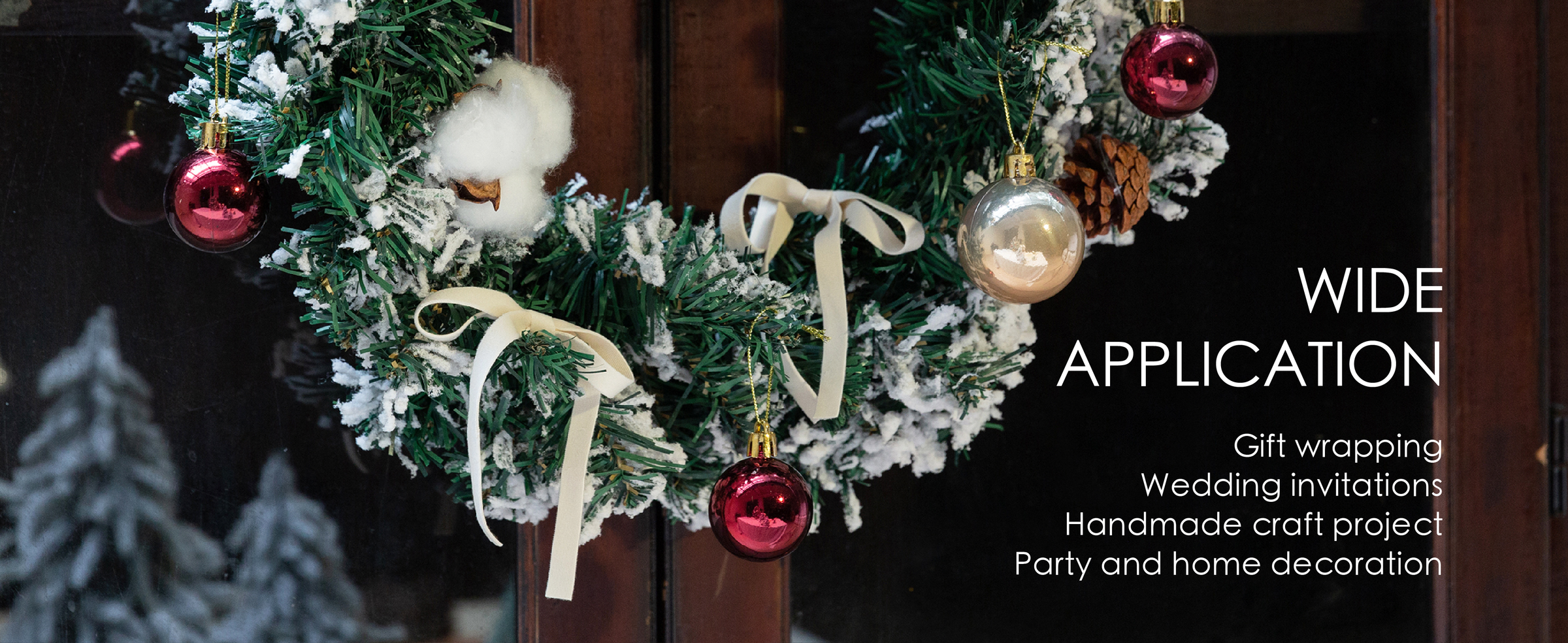 Ivory velvet ribbon bows decorate a snowy holiday wreath with pinecones and colorful baubles.
