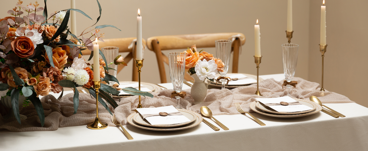 Neutral velvet ribbon accents place cards and glass stems on an elegant candlelit floral table.