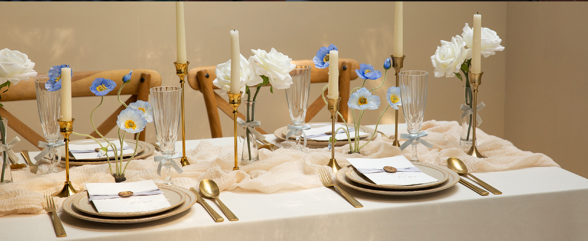 Blue and purple velvet ribbon set styled across a dining table with flowers, candles, and place settings