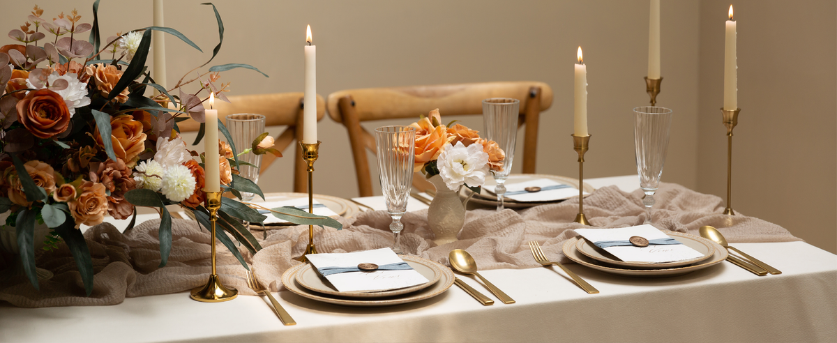 Blue velvet ribbon set styled across a dining table with flowers, candles, and place settings