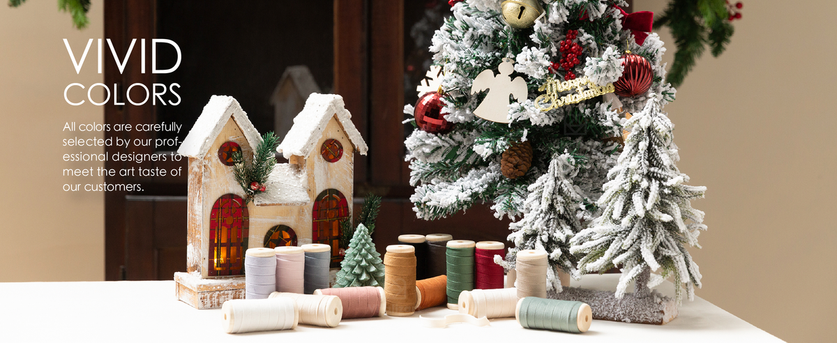 Colorful velvet ribbon spools displayed beside a snowy Christmas tree decorated with red bows.