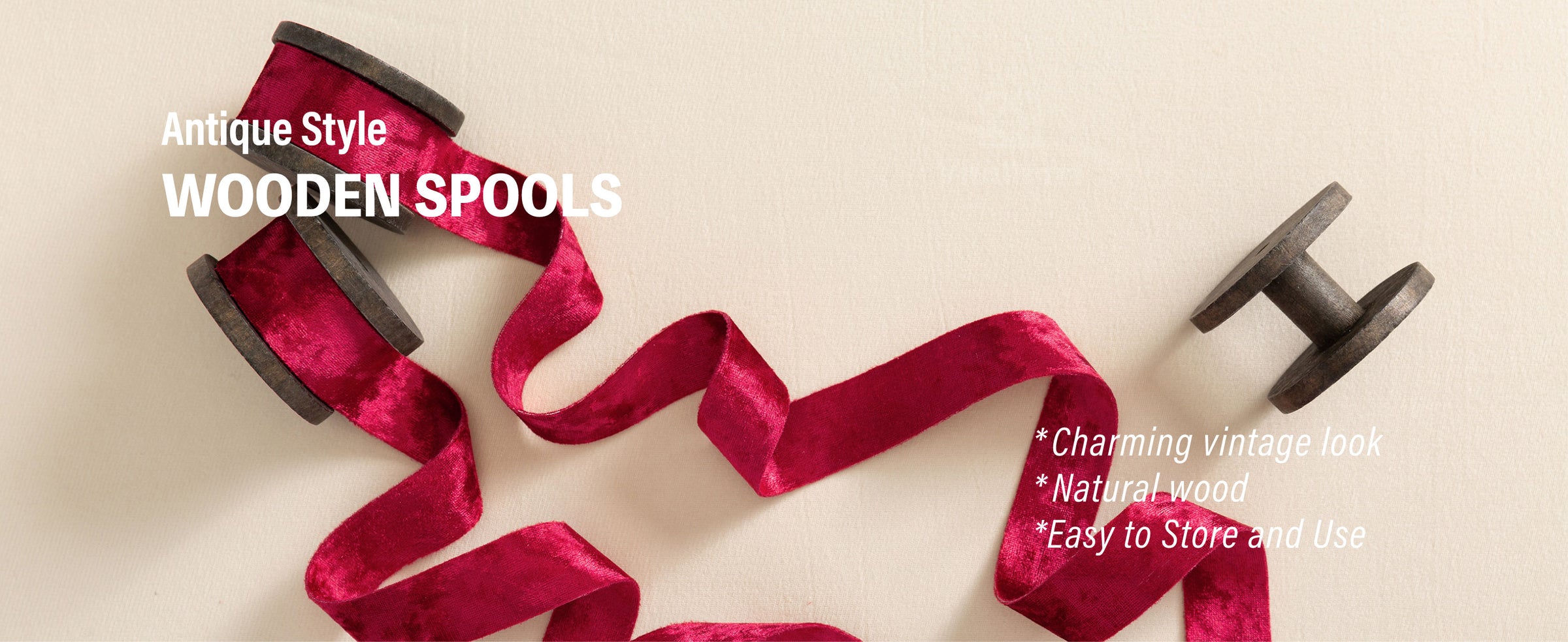 Deep red crushed velvet ribbon flowing from antique-style dark wooden spools across cream fabric
