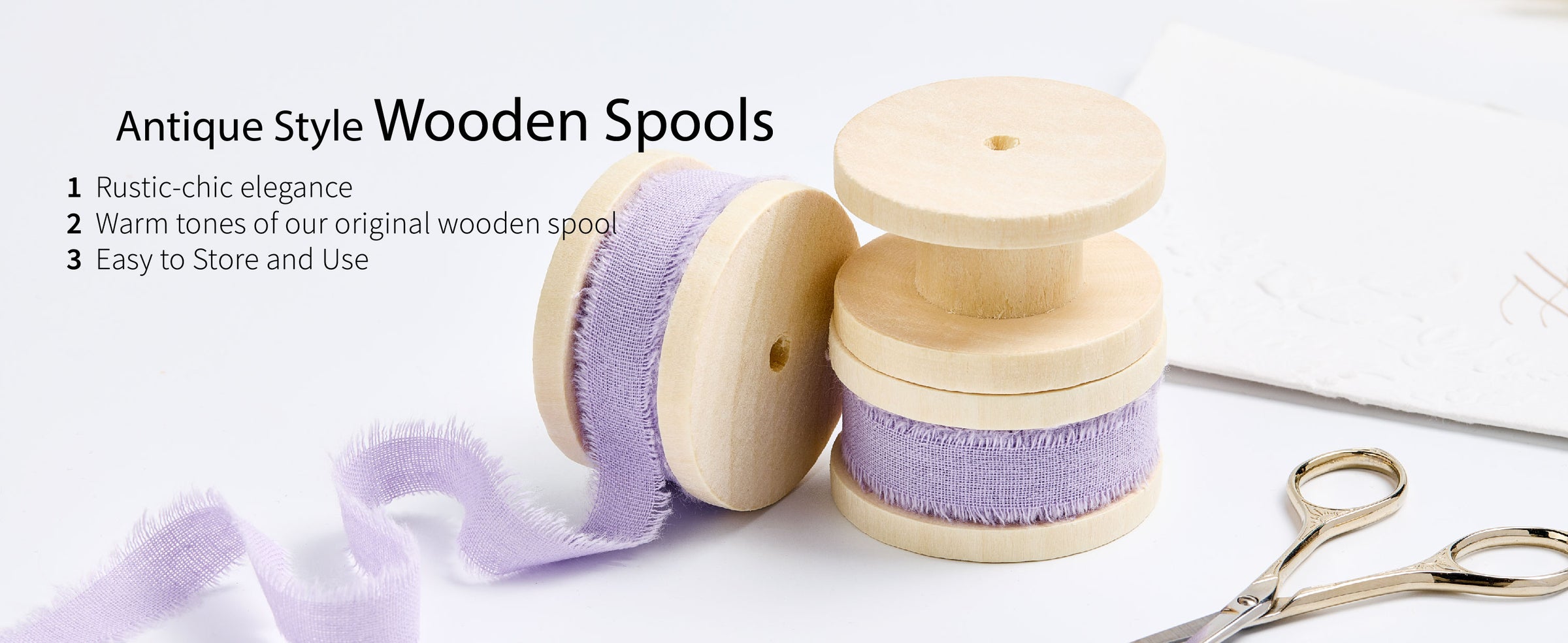 Lavender frayed cotton ribbon on pale wooden spools beside gold scissors and a loose ribbon trail