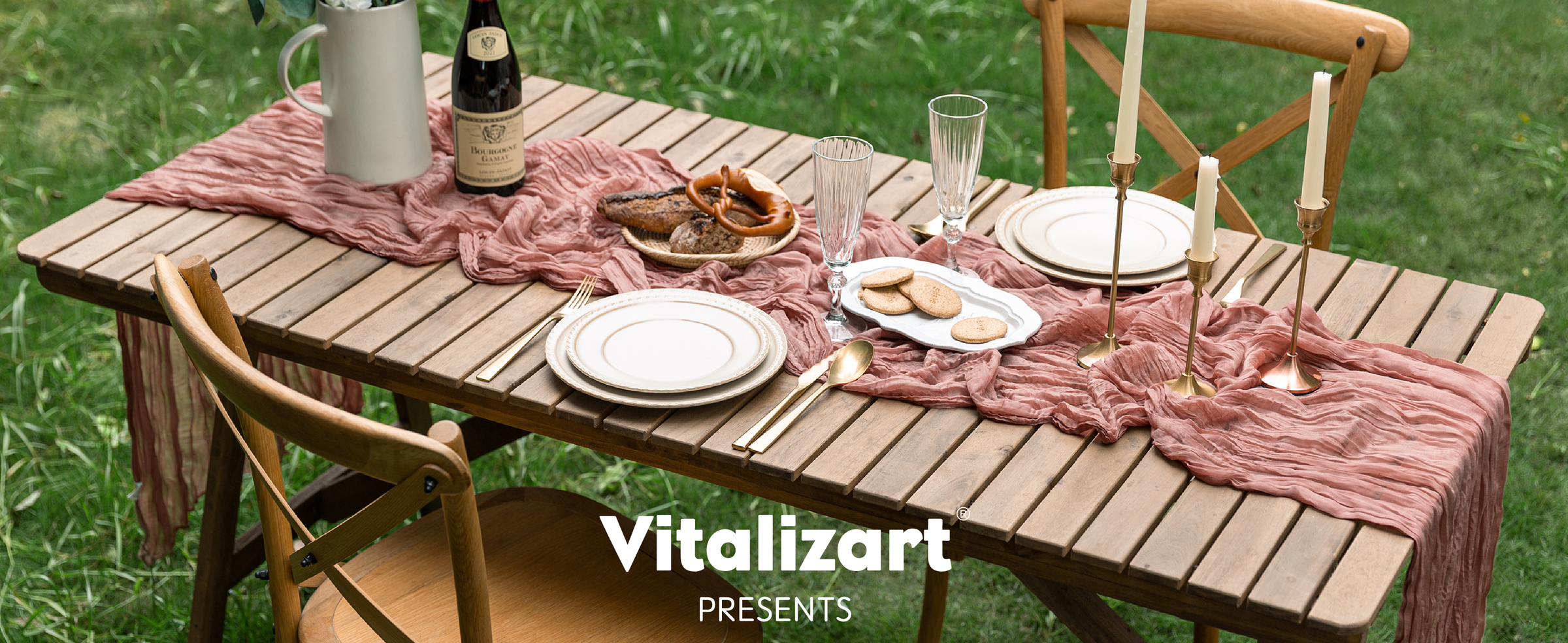 Peach-coral cheesecloth runner styled across an outdoor dining table with plates, candles, and flowers