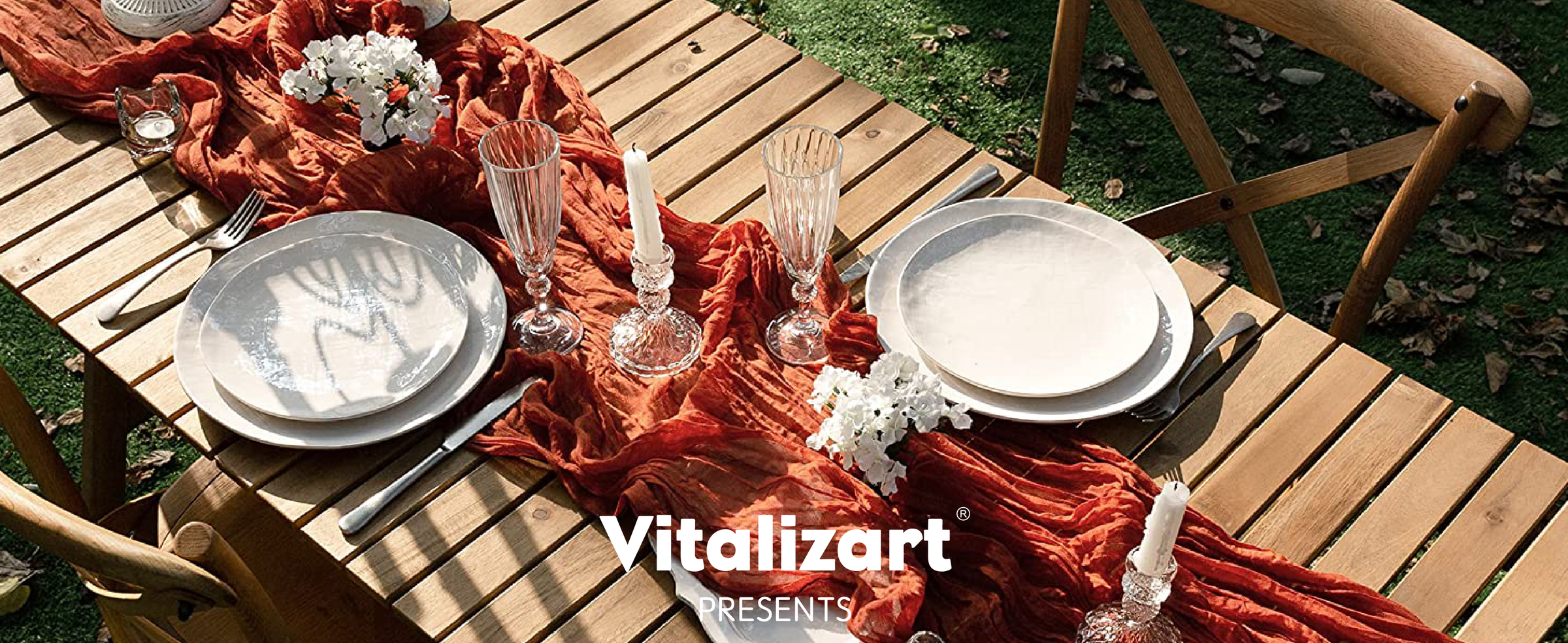Terracotta cheesecloth table runner styled with white place settings, flowers, and candles on an outdoor table.
