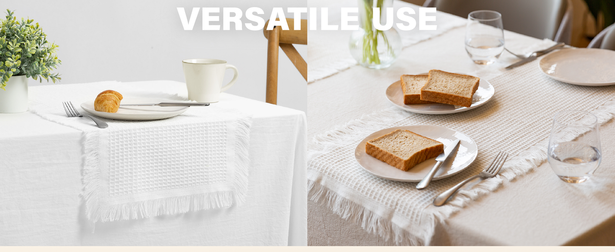 Folded white waffle-weave table runners with fringed edges arranged on a wooden bench