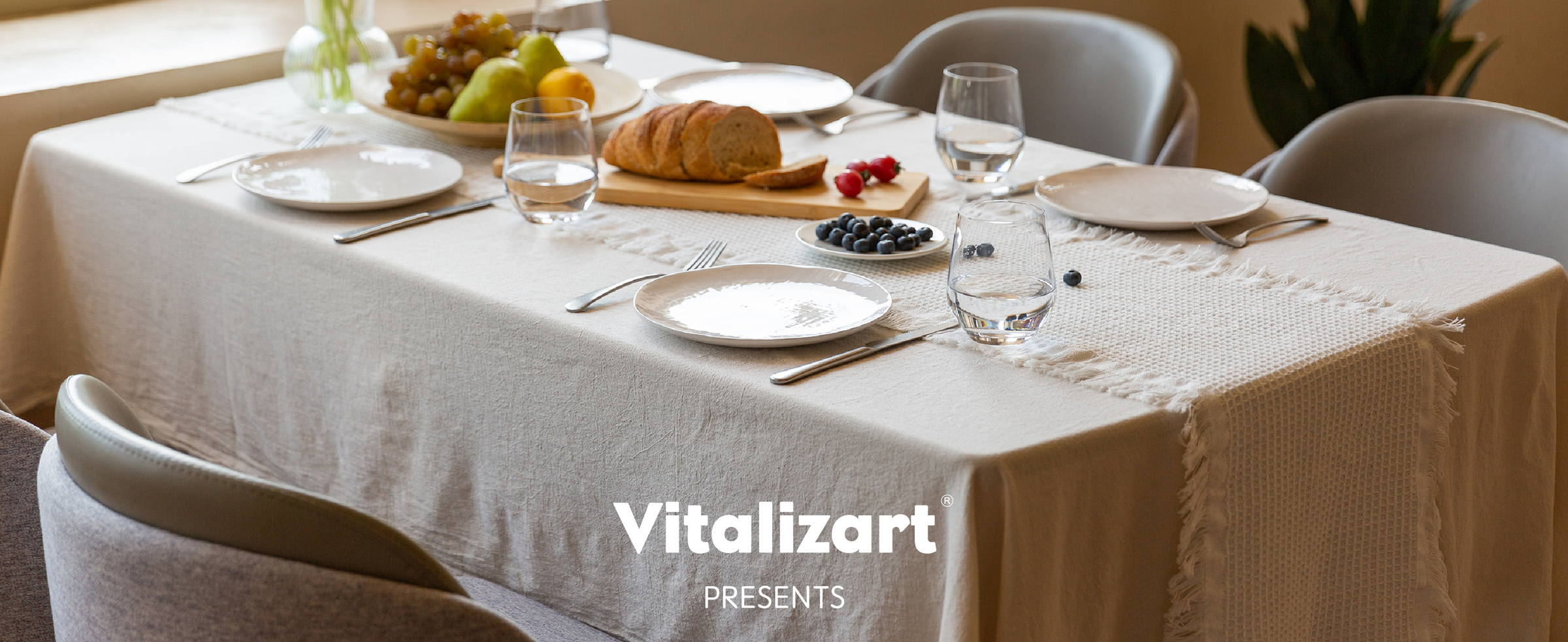 White fringed waffle-weave table runner on a sunlit dining table set with bread, fruit, and flowers