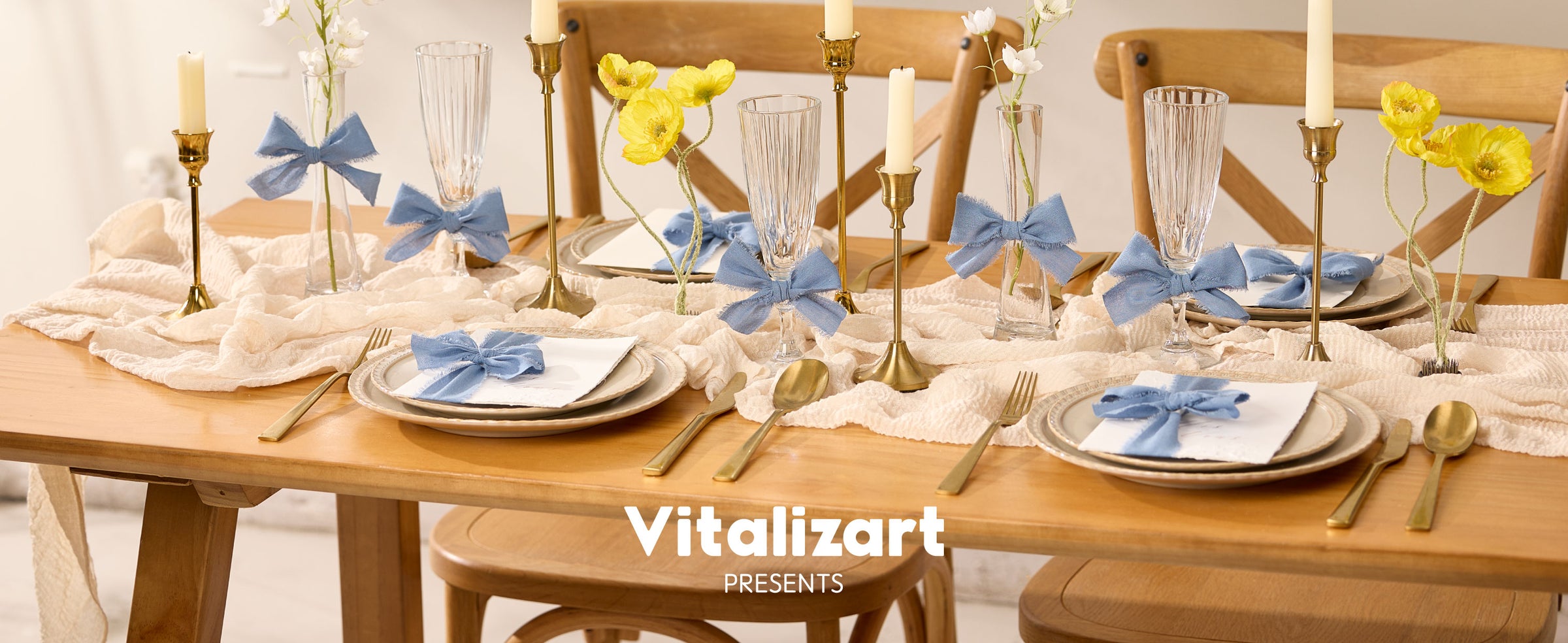 Dusty blue cotton ribbon bows decorate napkins, glasses, and flower vases on a warm dining table.