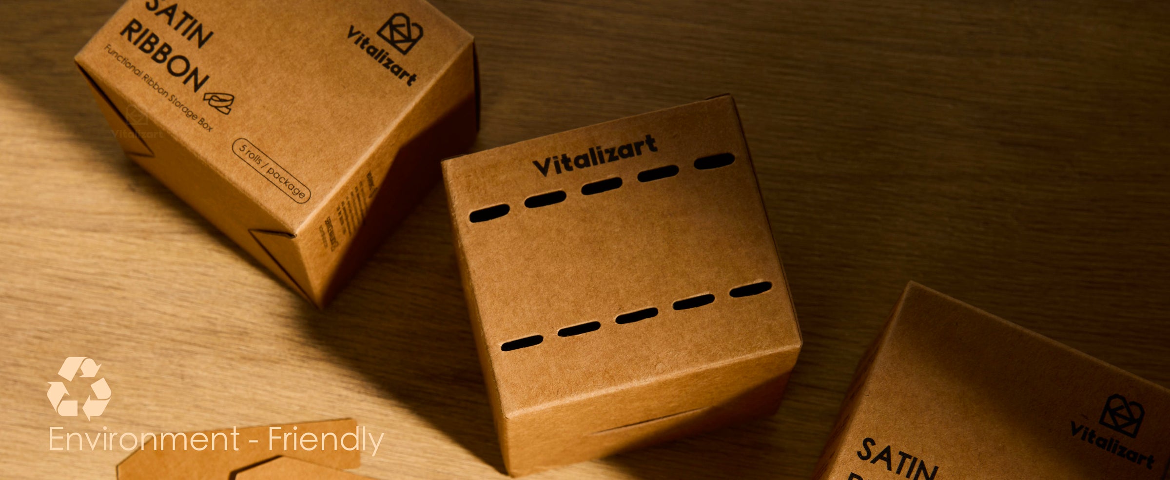 Kraft ribbon storage boxes and flat cardboard inserts arranged on a wooden table under warm light.