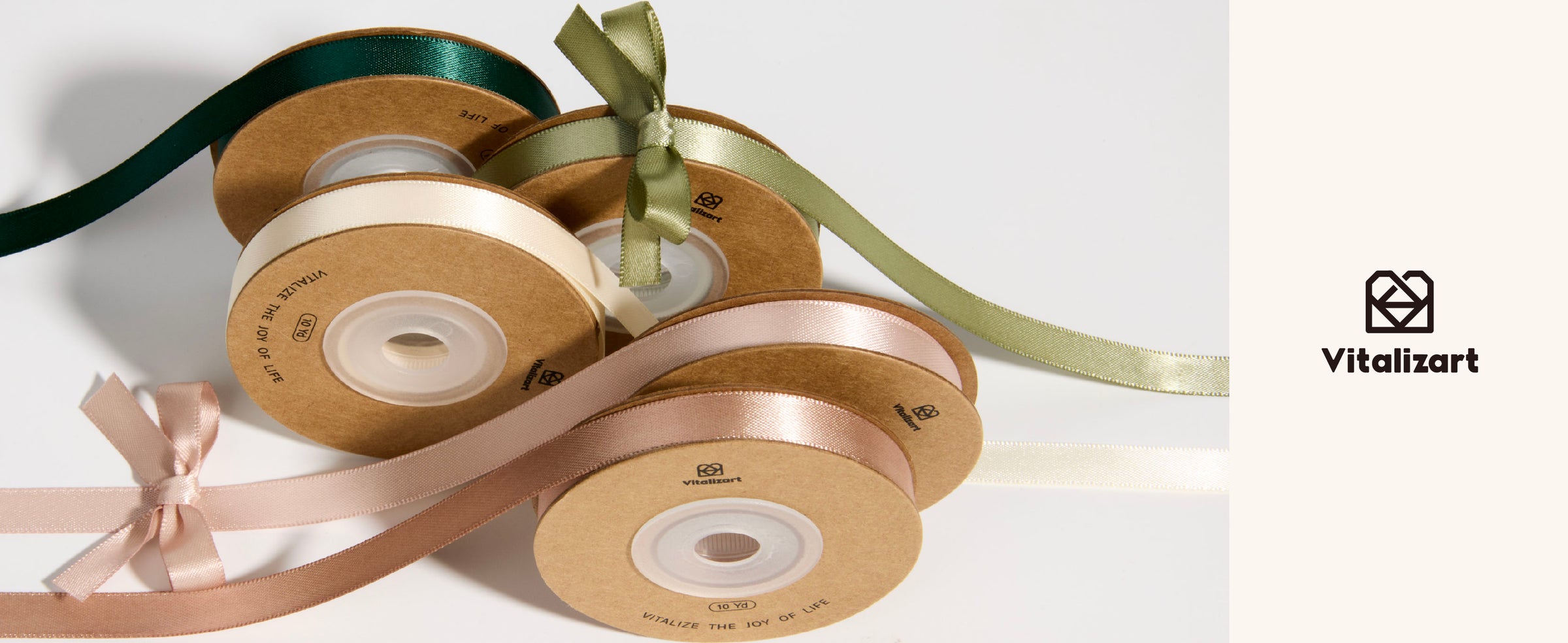 Five satin ribbon spools in dark teal, sage, ivory, and blush with loose lengths and bows.