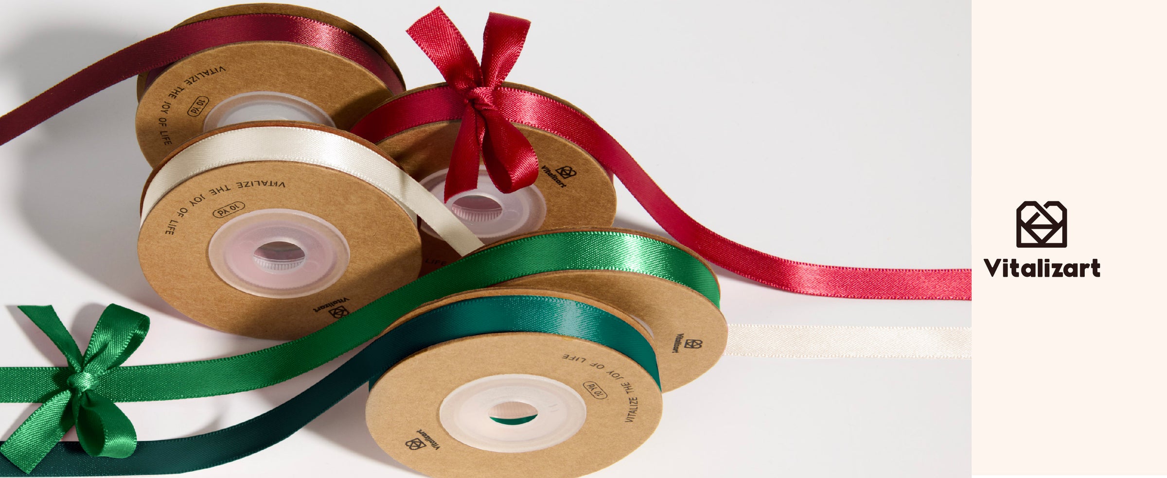 Five satin ribbon spools in burgundy, red, cream, green, and teal with loose bows.
