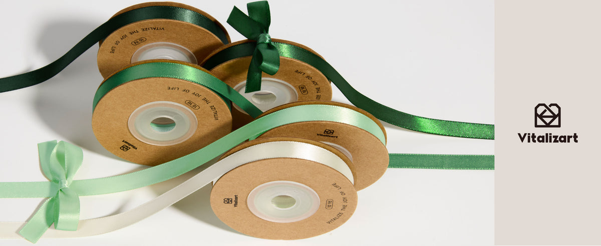 Five satin ribbon spools in forest green, emerald, mint, pale green, and cream with loose bows.