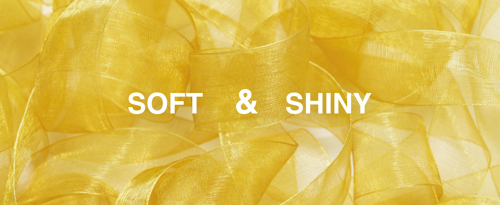 Close-up of soft, shiny gold sheer organza ribbon arranged in overlapping loose loops.