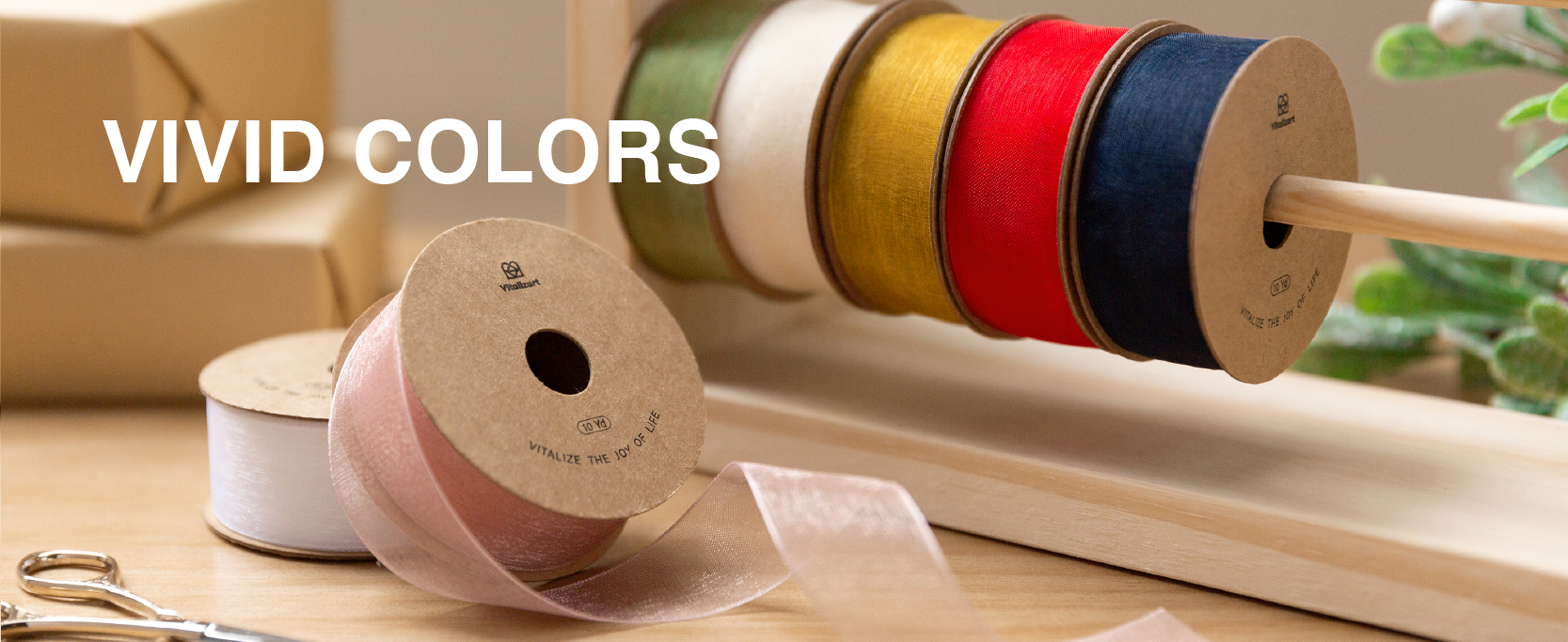 Sheer organza ribbon spools in green, white, gold, red, navy, and pink displayed on a wooden rack.