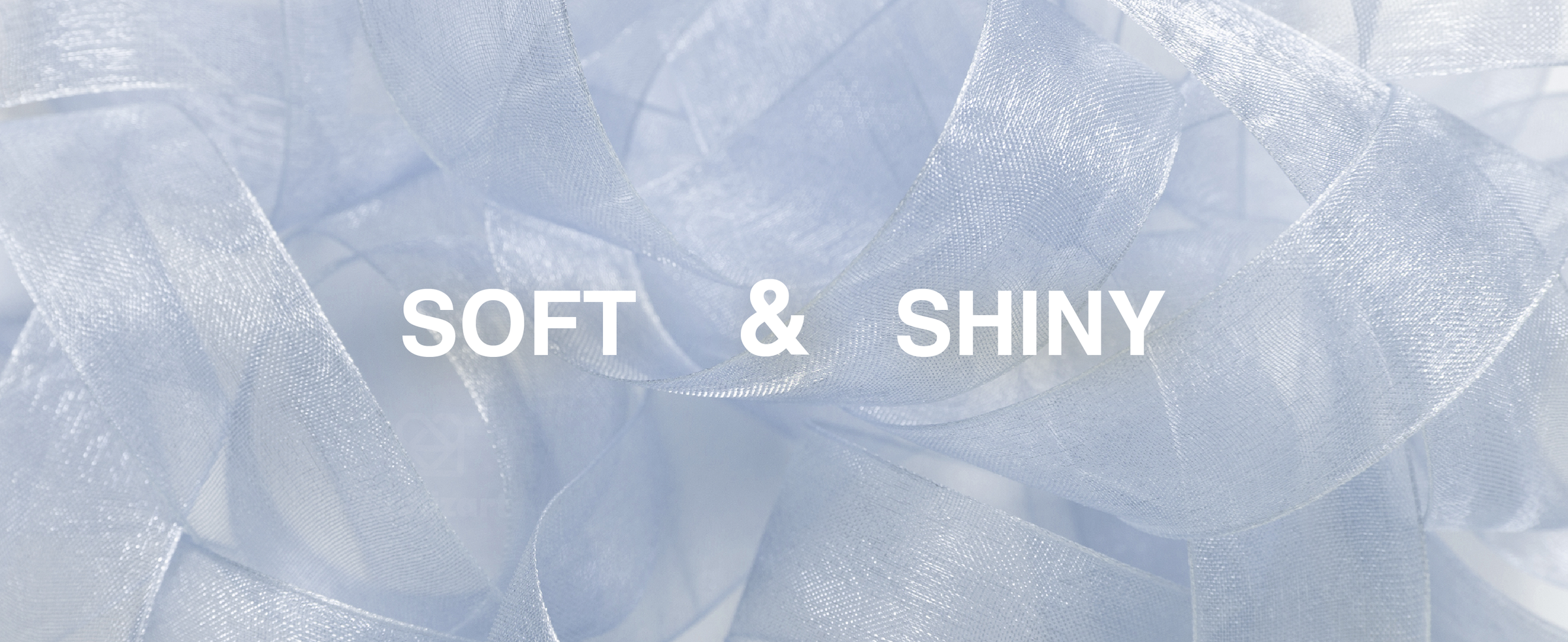 Close-up of soft, shiny blue-gray organza ribbon arranged in translucent overlapping loops