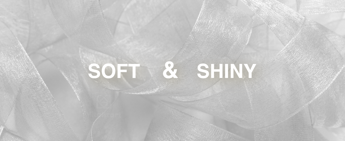 Close-up of soft, shiny silver-white organza ribbon in broad translucent loops.