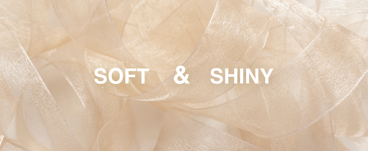 Close-up of soft, shiny champagne-gold organza ribbon arranged in broad translucent loops.