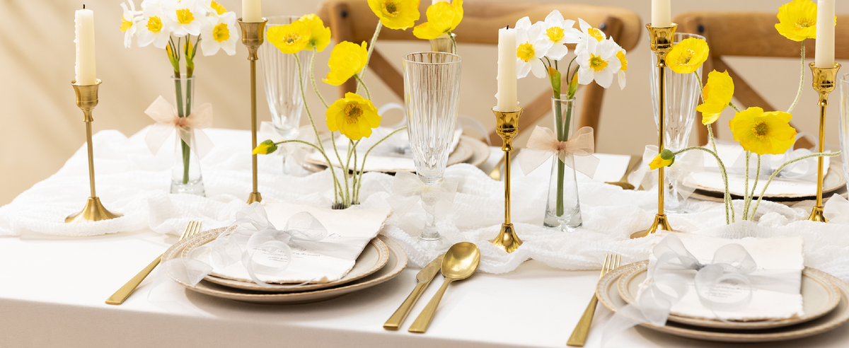 White sheer organza ribbon bows decorate napkins, glasses, and flower vases on a formal table