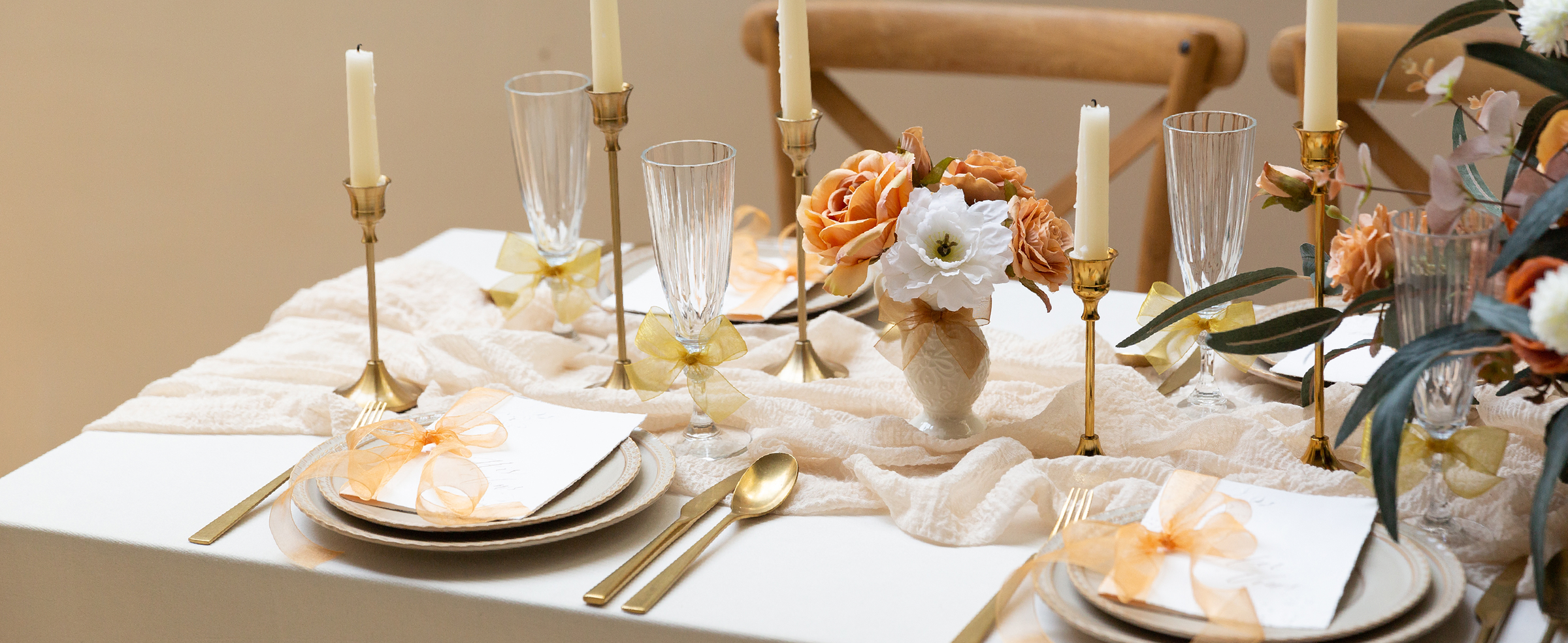 Gold and peach sheer organza ribbon bows decorate napkins, glasses, and vases on a formal table