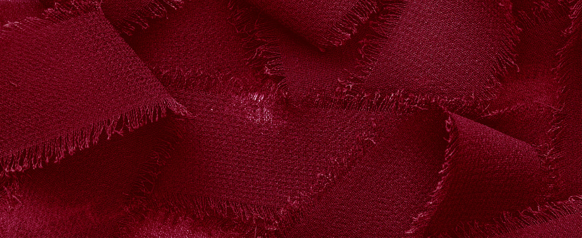 Close-up of overlapping deep red chiffon ribbon with fine weave and soft frayed edges