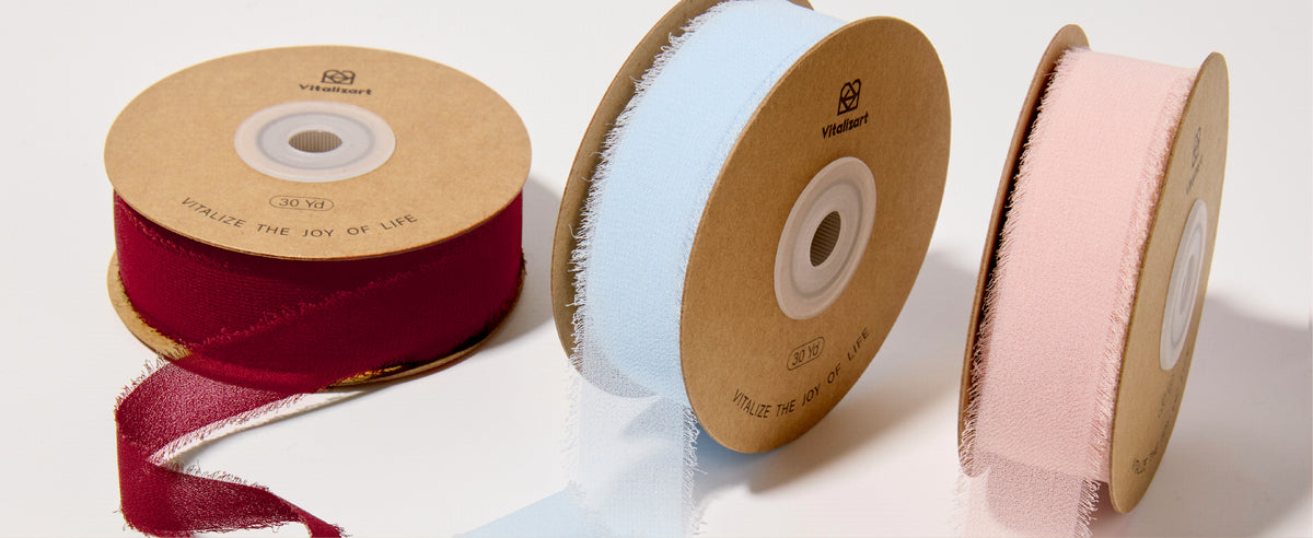 Red, pale blue and blush pink chiffon ribbon spools with loose, softly frayed lengths
