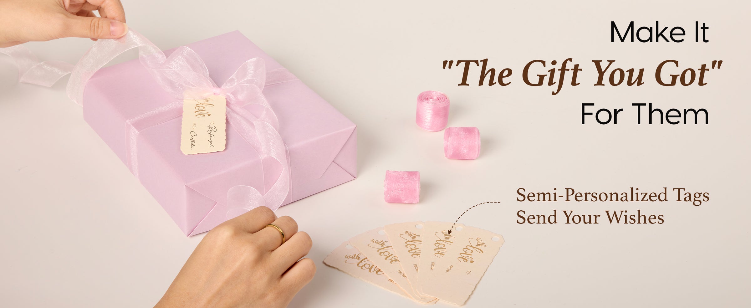 A hand presenting a gift wrapped in blush pink pearly paper with matching accessories