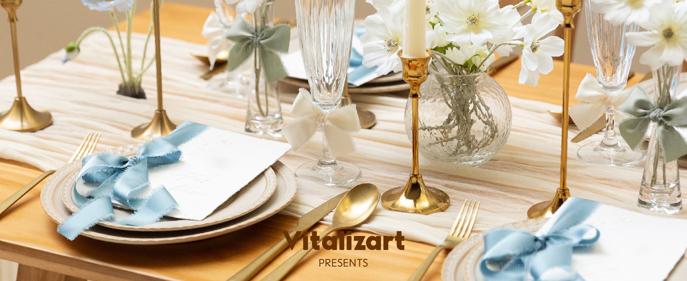 Dusty blue satin ribbon decorates place cards and settings on an elegant candlelit dining table.