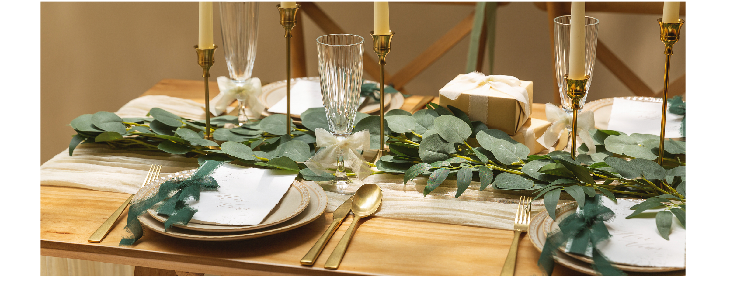 Green, blue, and ivory chiffon ribbons accent gifts, glasses, cards, and chairs on a formal table