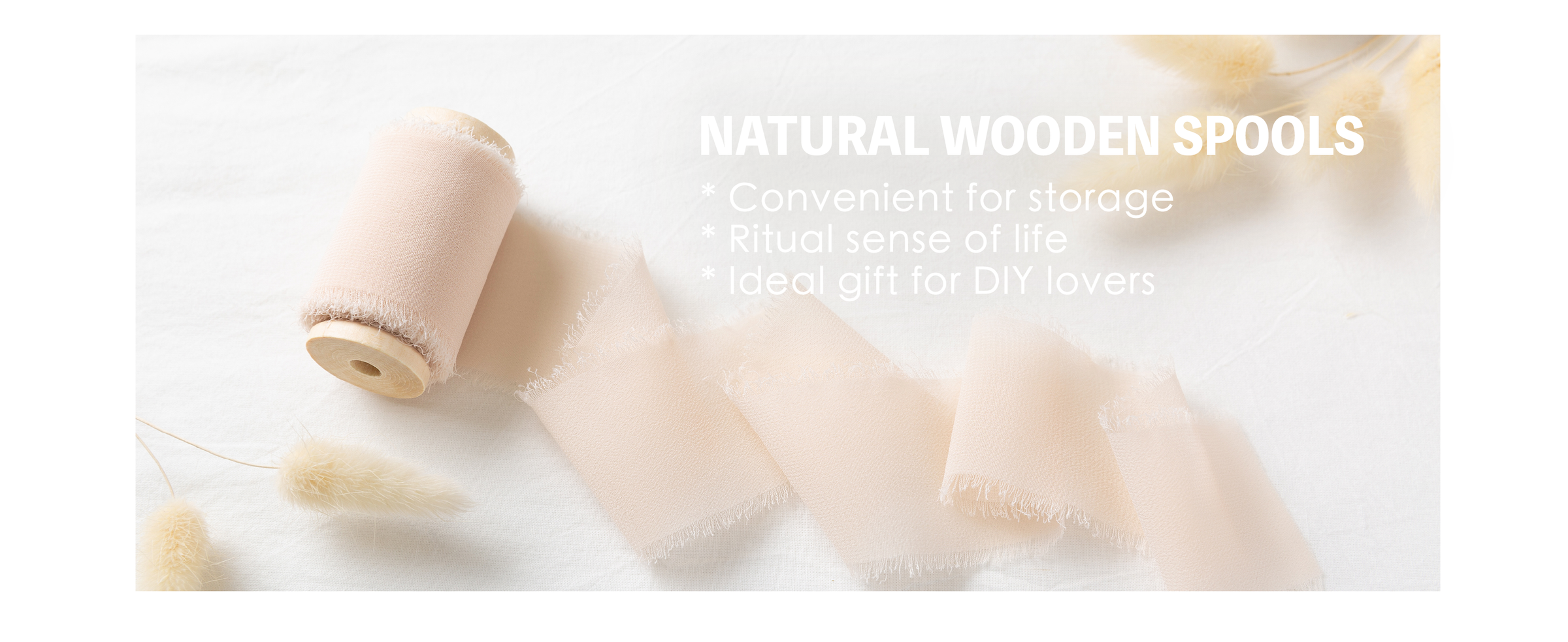 Light nude chiffon ribbon with frayed edges unfurling from a natural wooden spool on white fabric.