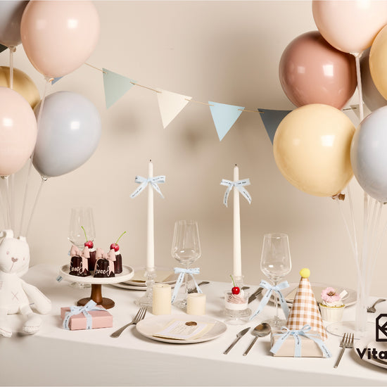 Pastel baby shower table setting with ribbon-wrapped favors and balloons