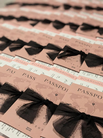 Pink passport wedding invitations tied with black chiffon ribbon bows